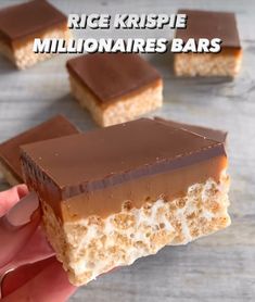 a hand holding a piece of chocolate and marshmallow bars with the words rice krispie millionaires bars on it