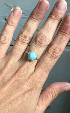 A stunning ethereal sky ocean blue round larimar has been set in sterling silver with a handmade ring band from sterling silver half dome wire. The stone is 11mm round and has interchanging hues of light and white running throughout. Choose your stone from the last photo in the listing. This will be the exact stone used in your ring!Larimar is the embodiment of the tranquil Sea and Sky energies. Its soft, soothing blues and calming turquoise is streaked with white patterns that resemble sunlight Turquoise Larimar Cabochon Jewelry, Adjustable Round Aquamarine Jewelry, Adjustable Aquamarine Jewelry, Adjustable Larimar Jewelry For Anniversary, Adjustable Aquamarine Round Jewelry, Blue Larimar Round Rings, Adjustable Aquamarine Bracelet, Round Larimar Jewelry For Gifts, Round Larimar Jewelry Gift