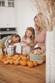 three children and an adult are in the kitchen preparing oranges for juice or smoothies