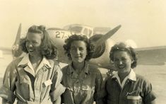 three women standing next to each other in front of an airplane