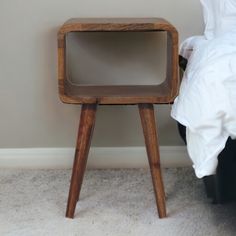 a small wooden table sitting on top of a carpeted floor next to a bed