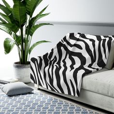 a zebra print blanket on a couch next to a potted plant