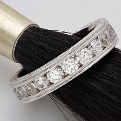 a black and white brush with some diamonds on it's side next to a piece of jewelry