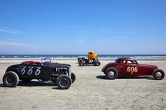 three antique cars are parked on the beach