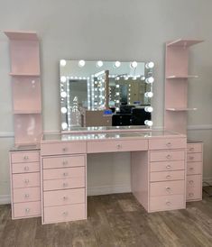 a pink vanity with lighted mirror and drawers