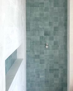 a white toilet sitting in a bathroom next to a walk in shower and tiled walls