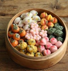 a wooden bowl filled with lots of small fake vegetables on top of a wooden table