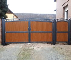 a large wooden gate in front of a brick house with black iron work on it