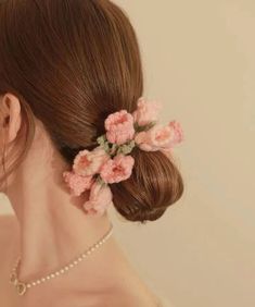 a woman with flowers in her hair is wearing a pearl necklace and pink flower clip