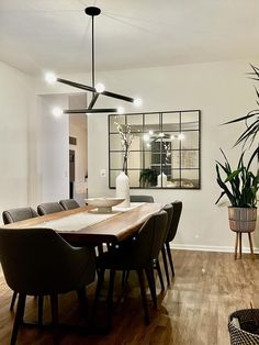 the dining room table is surrounded by black chairs and potted plants on either side