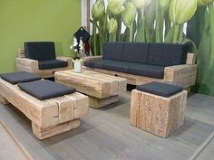 a living room with wooden furniture and green wall behind the couch, coffee table and ottoman