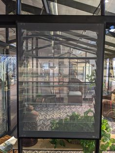 the inside of a glass house with lots of plants and furniture in it's windows