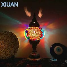 a colorful lamp sitting on top of a table next to cd's and cds