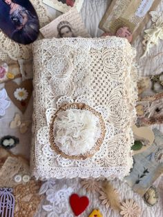 an old book with lace and buttons on the cover is surrounded by other vintage items