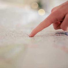 a close up of a person's finger pointing at something on a map with blurry lights in the background