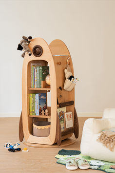 a wooden book shelf with books and stuffed animals on the floor next to other toys