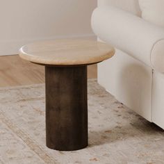 a white couch sitting next to a wooden table on top of a carpeted floor