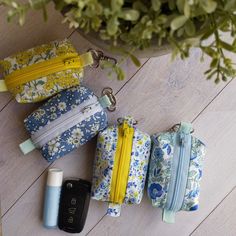 four zippered pouches sitting next to each other on a wooden floor near a potted plant