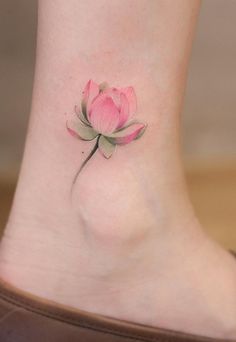 a small pink flower tattoo on the ankle