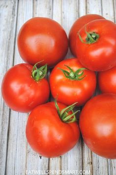 a pile of tomatoes sitting on top of a wooden table