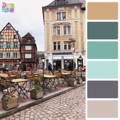 an outdoor cafe with tables and chairs in the middle of a cobblestone street