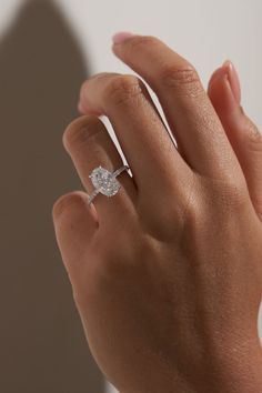 a woman's hand with a diamond ring on her left hand, against a white background