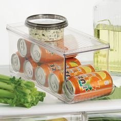 several cans of soda and celery on a refrigerator shelf with other food items