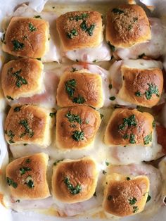 a casserole dish filled with meat, cheese and bread rolls covered in parsley