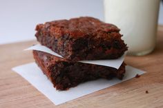 two brownies sitting on top of each other next to a glass of milk