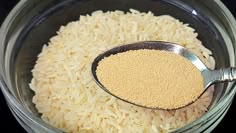 a glass bowl filled with rice and a measuring spoon