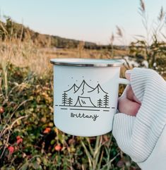 a person holding a white coffee cup in front of some bushes and trees with the words birthday written on it