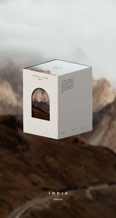 a white box hanging from the side of a mountain with an image of mountains in the background