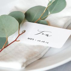 a white plate topped with green leaves and a name tag on it's side