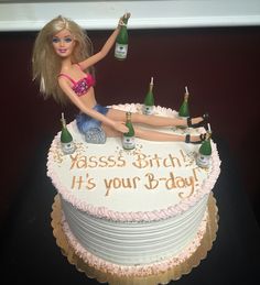 a barbie doll sitting on top of a birthday cake