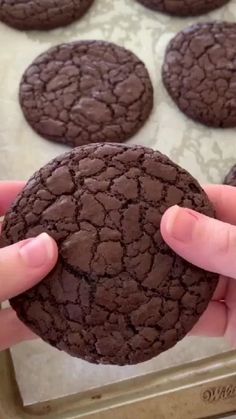 a person is holding up a chocolate cookie