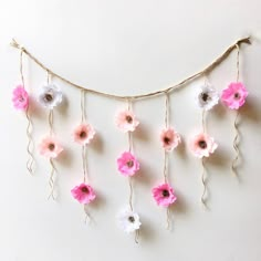 pink and white flowers are hanging from a string