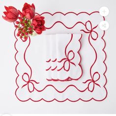 red flowers are sitting on top of white napkins that have been embroidered onto them