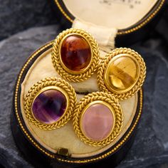 These playful cufflinks have twisted borders around oval cut cabochons that including rose quartz, amethyst, garnet, and citrine. The faces were originally interchangeable to change the gems to match a gentlemans color scheme. The cufflinks have hallmarks from Vienna, Austria, indicating they are true vintage. The cufflinks are crafted in 18k yellow gold. Gold Cabochon Gemstones For Formal Occasions, Formal Gold Cabochon Gemstones, Vienna Austria, True Vintage, Oval Cut, Vienna, Color Scheme, Citrine, Austria