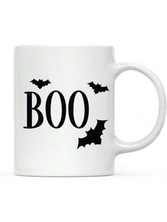 a white coffee mug with bats and boo written on the side, in black ink