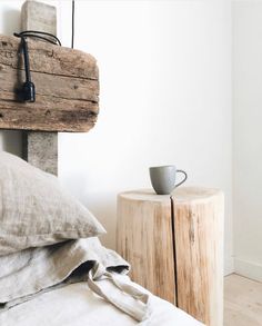 a cup is sitting on top of a bed next to a wooden headboard and night stand