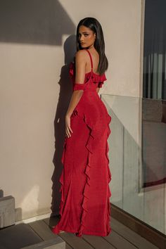 a woman in a red dress leaning against a wall with her back to the camera