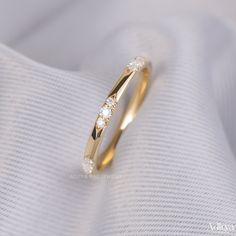 a yellow gold ring with three diamonds on it's side, sitting on top of a white cloth