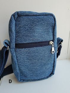 This bag is perfect for those who don't want to carry around a big bag, but still have a few things to carry. It's made with upcycled denim and has a pretty cotton lining.   The zippered main compartment is about 5 inches wide, 8 inches tall, and 2 1/2 inches deep.  The lightly padded inside phone pocket is about 4 1/2 inches wide and 5 1/2 inches deep and is perfect to keep your phone easy to grab and scratch-free. The outer pocket is about 4 1/2 inches wide and 5 inches deep and has a zipper to keep your cash and ID card safe and secure.  The outside of the bag also has a clip to easily hook your keys onto. The strap is made with sturdy cotton strapping and metal hardware that matches the zippers. The strap measures 30 inches to 54 inches long so it can be worn as a shoulder bag or a cro Denim Blue Cotton Shoulder Bag With Zipper Pocket, Denim Blue Cotton Bag With Zipper Pocket, Denim Blue Cotton Shoulder Bag With Zipper Closure, Denim Blue Cotton Bag With Zipper Closure, Denim Blue Bags With Cell Phone Pocket For Everyday, Denim Blue Bag With Cell Phone Pocket For Everyday, Everyday Denim Blue Bag With Cell Phone Pocket, Everyday Denim Zipper Pouch Bag, Casual Denim Shoulder Bag With Cell Phone Pocket