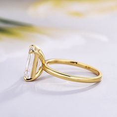 a yellow gold ring with an emerald cut diamond