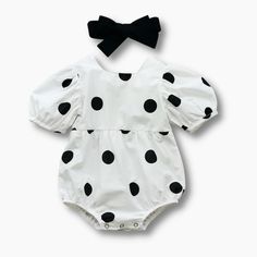 Introducing our charming Black Polka Dot Baby Romper, a must-have for your little one's wardrobe. This adorable romper features a white base with an all-over black polka dot pattern, adding a touch of playful elegance to their outfit. Designed with short sleeves and a square neckline, this romper is both stylish and comfortable. The buttons in the back make it easy to put on and take off, ensuring hassle-free dressing for busy parents. The cinched elastic at the legs provides a secure and comfor Black Cotton Onesie For Spring, Spring Cotton Black Onesie, Spring Black Cotton Onesie, Black Summer Onesie For Playtime, Playful White Fitted Jumpsuits And Rompers, Fitted Black Onesie For Summer, White Fitted Casual Bubble Romper, Fitted White Bubble Romper For Spring, White Fitted Bubble Romper For Playtime