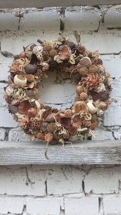 a wreath is hanging on the side of a white brick building with an assortment of dried flowers