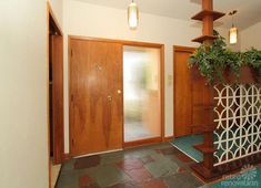 an entry way with wooden doors and green plants on the ledges in front of it