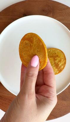 a person is holding two pieces of food on a white plate with pink nail polish