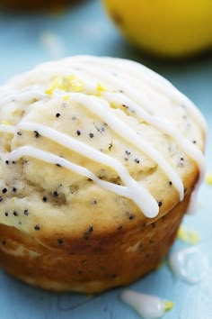 a muffin with white icing and sprinkles sitting on a blue surface