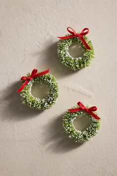 three small wreaths with red bows on them